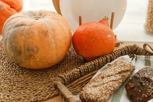 Kitchen countertop by the window in a bright room. Orange pumpkins, bread and pasta on the countertop. Autumn mood at home. photo