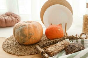 Kitchen countertop by the window in a bright room. Orange pumpkins, bread and pasta on the countertop. Autumn mood at home. photo