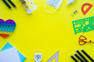 Close up of stationery and silicone toy popit. Flat lay composition. Yellow background. Space for text. Back to school photo