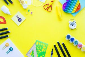 Close up of stationery and silicone toy popit. Flat lay composition. Yellow background. Space for text. Back to school photo