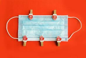 Christmas decorations decorative background. Decorative pins in the form of red gloves on the medical mask. Top view, minimalism, flat layout. Christmas and New year 2020. The Age Of Coronavirus. photo