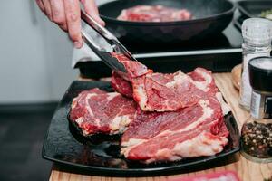 Raw beef meat for steak preparation. Raw beef sliced, preparation of meat for cooking steak at the culinary master class. Raw meat on a black plate. photo