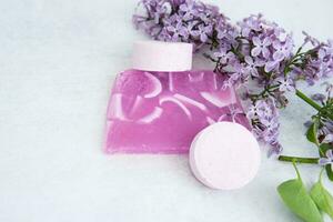 Concept of Spa-cosmetic and cosmetic procedures. Bath salt in effervescent tablets and handmade soap with lilac flowers on light concrete background. The concept of a waste-free lifestyle. photo