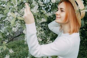 Portrait of a woman in a straw hat in a cherry blossom. Free outdoor recreation, spring blooming garden. photo