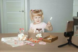 A little girl blogger makes a sweet Valentine's Day gift with her own hands. A gift for the holiday, a video blog entry. photo