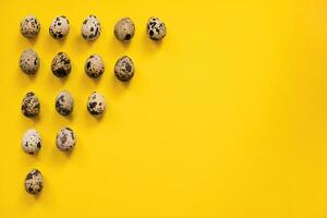 Quail Easter eggs on yellow background. Easter elements. Easter background. Easter pattern. Top view. Flat lay. Minimal concept. photo