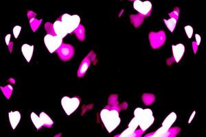 Blurry lights on a dark background. Festive bokeh background in the form of hearts for Valentine's Day. Soft focus. photo