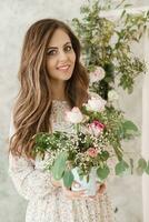 A brown-haired woman with long hair is having breakfast in a beautiful floral location. Spring portrait. photo