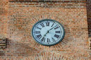 a clock on the side of a brick building photo