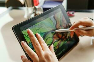 TVER, RUSSIA - FEBRUARY 11, 2023. A young woman draws neurography with a stylus on a tablet. Psychological session to remove restrictions, art therapy. photo