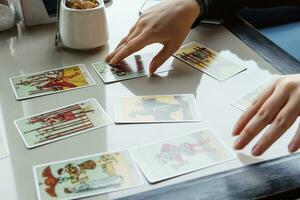 TVER, RUSSIA - FEBRUARY 11, 2023. Tarot cards, Tarot card divination, esoteric background. A woman makes a layout on the cards at the table. Divination, predictions on tarot cards. photo