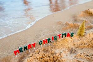 The inscription Merry Christmas on the seashore and photo