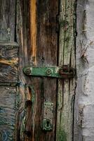 An old lock hinge on a cracked wooden door. Vintage Door photo