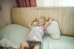 girl stretches lying in bed. small child rests in quarantine photo
