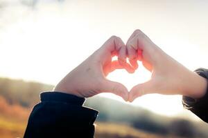 Child hands folded heart on the background of the winter sky. At photo