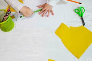 The child circles his hand with a pencil. The little girl learns to hold a pencil and is engaged in creativity. Copy space photo