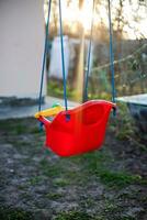 solitario vacío para niños columpio en yarda de casa. rayo de Brillo Solar que cae en patio de juegos. permanecer hogar concepto foto