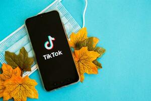 ver, Rusia, septiembre 25, 2020, médico máscara y tik tok logo en el teléfono inteligente pantalla en azul antecedentes. Tik Tok icono. el tik tok aplicación Tik Tok social red. otoño concepto. foto