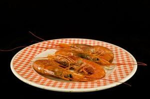 three large shrimp on a plate with a checkered pattern photo