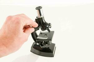 a hand holding a microscope on a white background photo