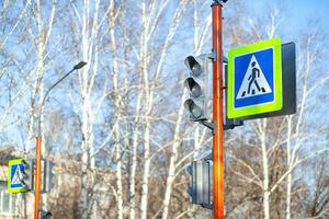 A pedestrian crossing sign with a reflective coating and traffic light photo