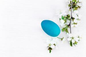 Easter background and branches of spring flowering cherries on white wooden background. eggs colored with natural dyes. Top view with copy space photo