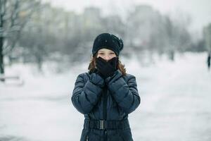 girl covered mouth with gloves. The girl made a gesture, silence. A child walks after school on the street in a snowfall. photo