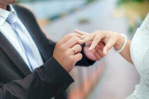 Groom wears bride a wedding ring on his finger. A couple betroth photo