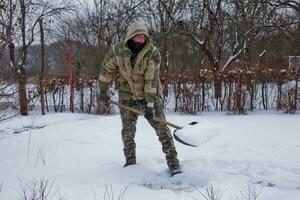 hombre borra el yarda de nieve con pala. pesado nevada en invierno. alto nivel de nieve. Nevado ventisquero. foto