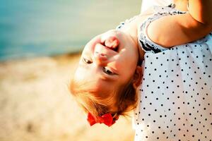 The little girl shows tongue. A child playing on the beach. Mom and baby are resting on the beach. Place for text. photo