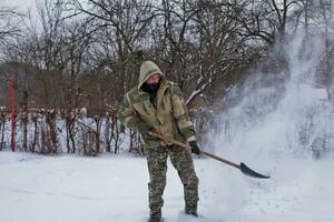 man clears the yard of snow With Shovel. Heavy snowfall in winter. High level of snow. Snowy snowdrift. photo