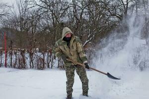 hombre borra el yarda de nieve con pala. pesado nevada en invierno. alto nivel de nieve. Nevado ventisquero. foto