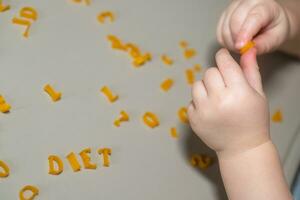 hand of child collecting letters from pasta from table. development of fine motor skills of hands. Montessori technique. Learn letters and alphabet in game photo