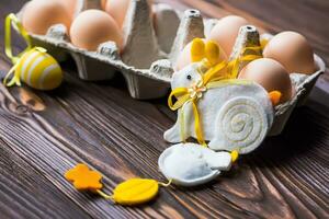 Cardboard tray with Easter eggs on a wooden table next to a bouquet of yellow tulips and Easter decor photo