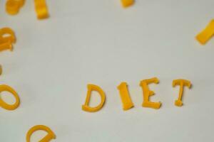 word DIET consists of edible letters. Pasta Diet Food. Pasta in form of letters on gray background. Proper nutrition concept. photo