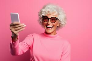 contento antiguo mujer con gris pelo sonriente felizmente y tomando selfie en rosado antecedentes generativo ai foto