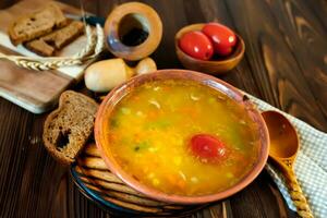 Pea soup with tomato on a wooden table. Tomato soup with sauerkraut tomatoes and a wooden spoon. Slovenian national dish. photo