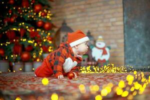 Little surprised child in santa costume in festive room on Christmas eve. Girl on background of Christmas tree. photo