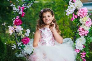 charming girl in a white dress sitting on a swing decorated with flowers photo