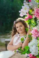 hermosa caucásico niña sentado en hermosa columpio con el vistoso rosas flor en el naturaleza jardín colgando en polo foto