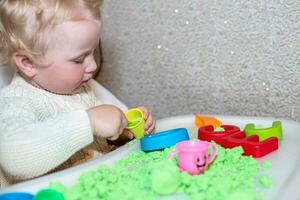 girl plays with kinetic sand. child builds shepherds in form of letters of sand. Early development of children. fine motor skills of the fingers. photo