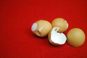 Several chicken egg shells, cracked and broken on red background photo