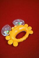 Yellow crab shaped children's toy, with small balls inside, makes a loud sound. On red background photo