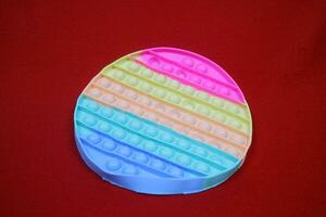 Colorful fidget pop toys, circular shape, which function to reduce stress. on red background photo