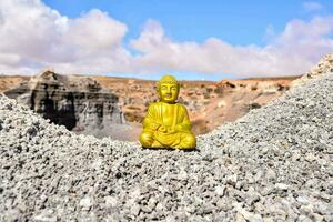 a yellow buddha statue sits on top of a pile of rocks photo