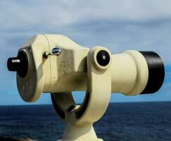 a telescope is on top of a pole near the ocean photo