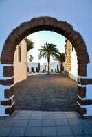 an archway in a white building with palm trees photo