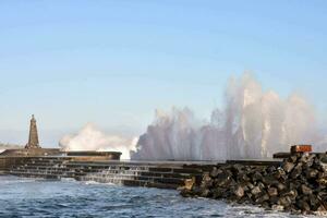 un grande ola salpicaduras dentro el agua cerca un muelle foto