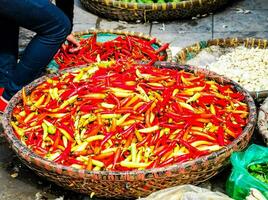 a woman is standing next to baskets of red and yellow peppers photo