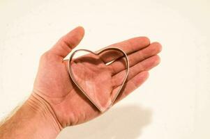 a hand holding a heart shaped cookie cutter photo